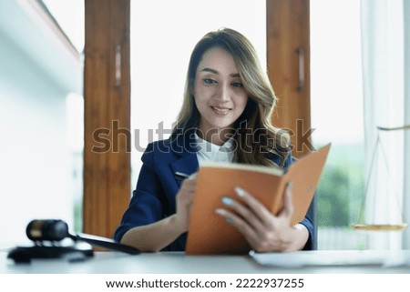 Portrait of a young Asian lawyer studying a lawsuit for a client using notebooks and paperwork on a desk.