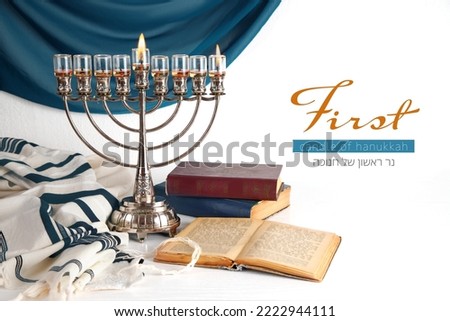 First candle of Hanukkah (Lettering in English and Hebrew)  with Menorah (traditional candelabra). Jewish religious holiday