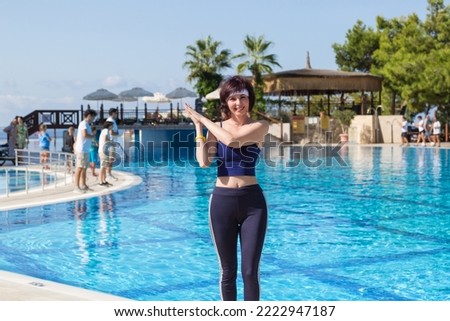 An adult female animator in a Turkish hotel by the pool with clear water.