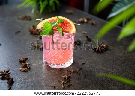 light alcoholic pink cocktail decorated with a slice of grapefruit and mint leaves in a glass of rocks type. Taken in close-up