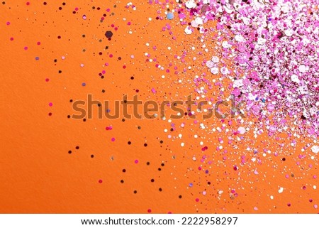 Shiny bright pink glitter on orange background, flat lay