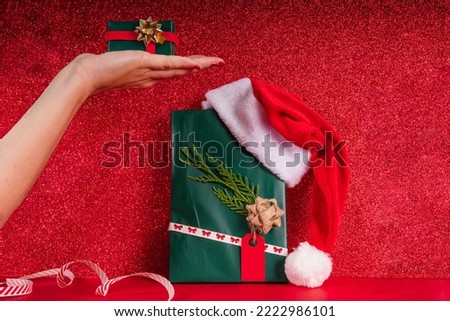Woman hand holding a small wrapped gift over a christmas background in frontal view with copy space