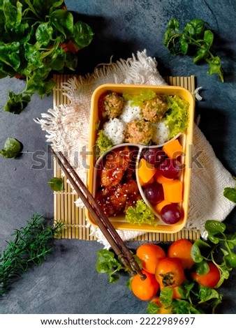 Meal box consist of mango, grape, rice, and stir fry chicken. Flat lay photography 