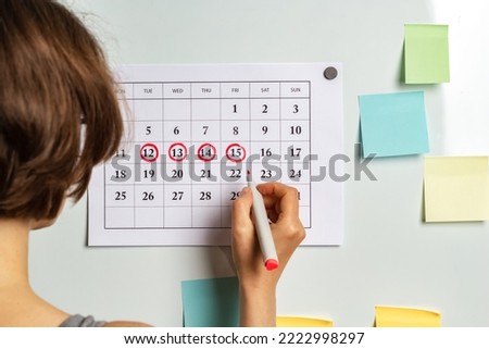 The concept of the menstrual cycle, ovulation period. The woman marks the days on the calendar. Royalty-Free Stock Photo #2222998297