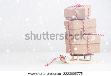 Boxes with gifts on a sled on a light background with space for text. Snow. Gifts for New Year and Christmas.