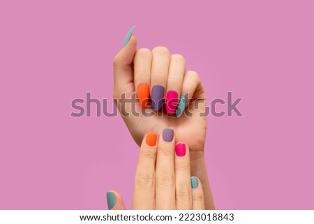 Female hands with colorful nail design. Glitter nail polish manicure: purple, green, pink, and orange. Female model hands with perfect colorful manicure on pink background. Copy space. Place for text. Royalty-Free Stock Photo #2223018843