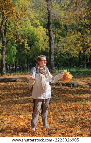 The photo was taken in the Odessa public park called the Dyukovsky Garden. In the picture, a girl in sunglasses put her palms up to the autumn sun in an autumn park.