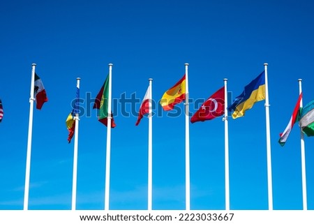Flags of Different Countries Hang On Flagpoles Against Blue Sky. Flag of Spain, Ukraine, Mexico, Germany, Sweden, Turkey and Poland. The concept of support and unity of countries. High quality photo Royalty-Free Stock Photo #2223033667