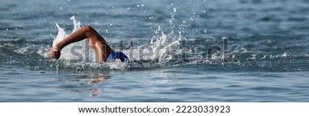 Professional triathlete swimming in ocean open water, male triathlon swimmer swimming in professional triathlon suit training Royalty-Free Stock Photo #2223033923