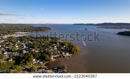 An aerial view over the Hudson River, upstate, NY. It's a sunny day and the river is calm and quiet, the trees are green and the skies are blue. Taking in relaxing views.
