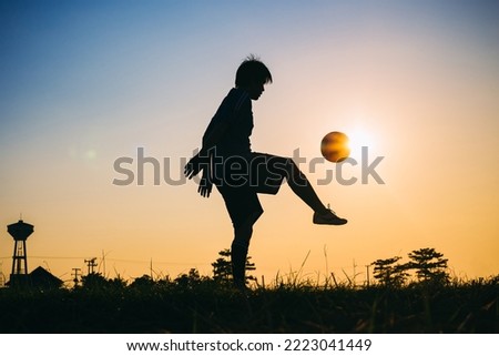 Silhouette action sport outdoors of football player on the sunset sky. Man kick soccer ball.