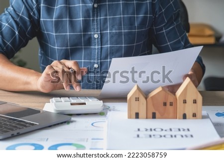 Accountant, businessman, real estate agent, businessman handing model house to customers along with house interest calculation documents for customers to sign.