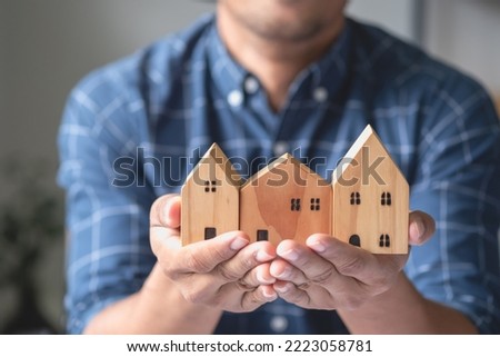 Accountant, businessman, real estate agent, businessman handing model house to customers along with house interest calculation documents for customers to sign.