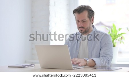 Busy Young Man Typing on Laptop in Office