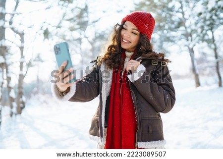 Smiling young woman taking selfie in winter forest. Winter holiday.