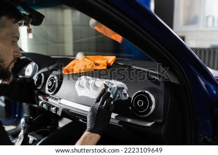 Foam and detergent cleaning interior in car using brush. Worker in auto cleaning service clean car inside. Car interior detailing Royalty-Free Stock Photo #2223109649