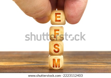 Business concept. A man puts wooden cubes on the table with the inscription - EFSM