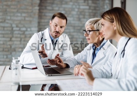 Group of doctors  cooperating while working on laptop  in a hospital