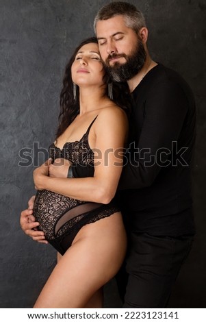 A pregnant woman with a man on a dark background
