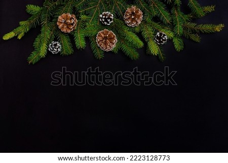 Christmas decorations, fir branches and cones on a black background. Top view with with copy space.