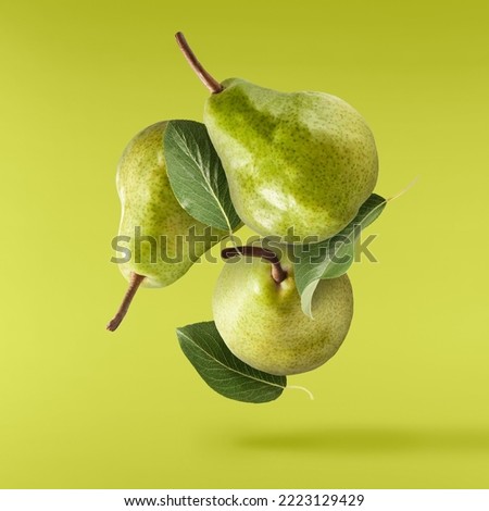 Fresh ripe green pear with leaves falling in the air, isolated on green background. Food levitation or zero gravity concept. High resolution image Royalty-Free Stock Photo #2223129429