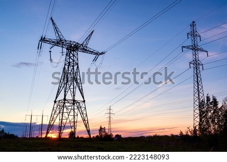 Sunset behind powerlines and pylons. Energy crisis and blackouts concept Royalty-Free Stock Photo #2223148093