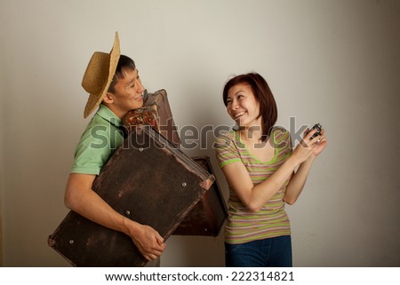 Girl takes pictures while the guy holding the bags