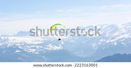 Paraglider Fly in the Mountains as snow apls mountain background