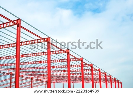 Red Cellular Beam Metal Structure of large Industrial Building in Construction Site against white cloudy sky in low angle and perspective side view Royalty-Free Stock Photo #2223164939
