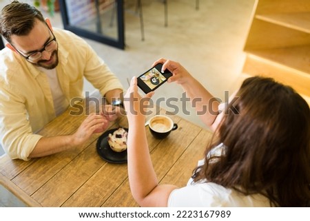 Top view of a happy couple on a date smiling while taking a photo of their dessert for social media