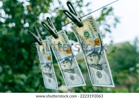 Three hundred dollar bills hanging on a clothes dryer pinned with clothespins close-up on a blurred background. Money laundering on a small scale. Corruption scheme for illegal receipt of money