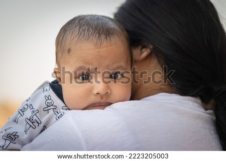cute infant facial expression resting at mother shoulder from flat angle