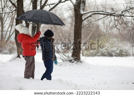 children in winter park play with snow
