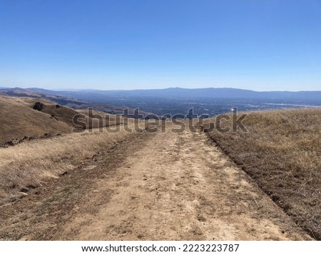 Unpaved hiking trail, fire road with aerial view of valley floor and San Francisco Bay during fall season.