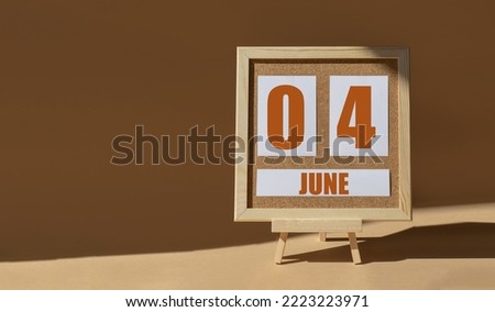 June 4th. Day 4 of month, Calendar date. Cork board, easel in sunlight on desktop. Close-up, brown background.  Summer month, day of year concept.
