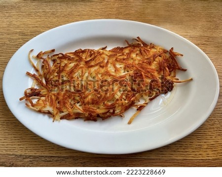  Very crispy hash brown potatoes served on a white plate.