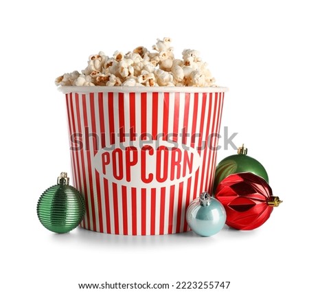 Bucket of popcorn and Christmas balls on white background