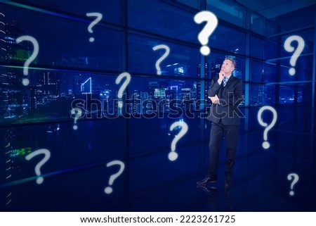 Caucasian businessman thinking something while standing with question mark symbol in the office with glowing city background