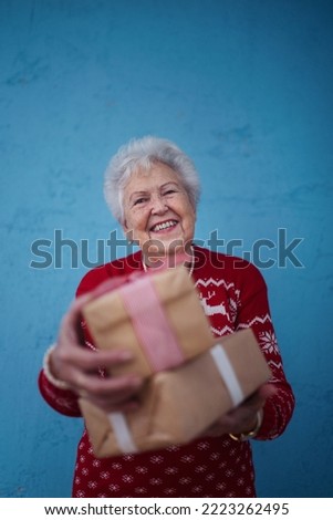 Portrait of happy senior woman holding gift, studio shooting.