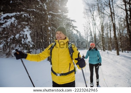 Senior couple skiing together in the middle of forest Royalty-Free Stock Photo #2223262965