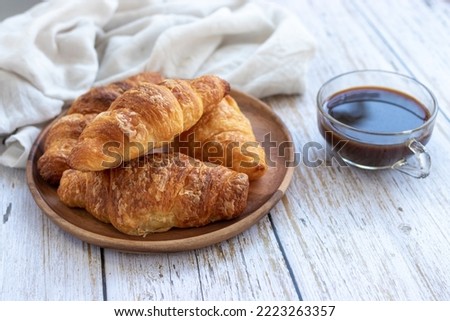 A cup of coffee and croissant on white table
