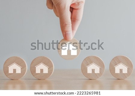Real estate, Property investment and asset management concept. Hand choosing house icon on wood circle from many house. Decision to choose the best property with your right. Choosing suitable housing.
