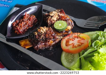Grilled beef ribs with Indonesian specialties complemented with chili sauce or sambal, fresh vegetables, and lime as a refreshment