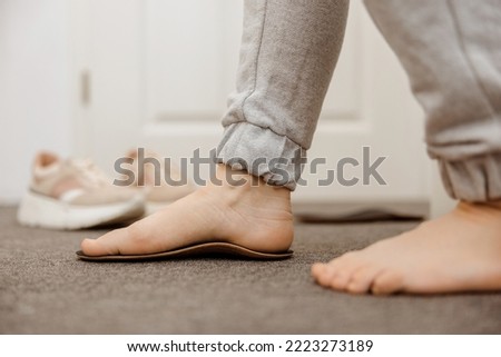 Flat feet diagnosis and orthotics, shoe inserts. Problems with flatfoot, pain. Identification of flat foot. Treatment to plantar fasciitis. Womans foot and insoles at home, close up view. Royalty-Free Stock Photo #2223273189