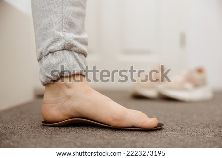 Flat feet diagnosis and orthotics, shoe inserts. Problems with flatfoot, pain. Identification of flat foot. Treatment to plantar fasciitis. Womans foot and insoles at home, close up view. Royalty-Free Stock Photo #2223273195