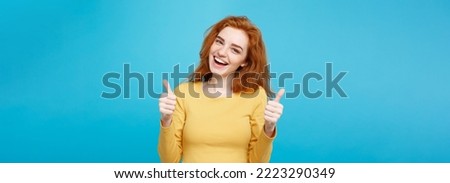 Portrait of young stylish freckled girl laughing with showing thumps up at camera. Copy space Royalty-Free Stock Photo #2223290349