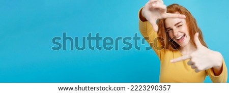 Portrait of young beautiful ginger woman with freckles cheerfuly smiling making a camera frame with fingers. Isolated on white background. Copy space