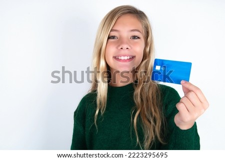 Photo of happy cheerful smiling positive caucasian teen girl wearing green knitted sweater over white background recommend credit card