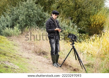 Photographer in the process of shooting on large-format retro camera. Shooting an autumn landscape with an old camera. Concept - old classic process, film camera. Selective focus.