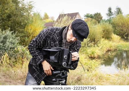 Photographer in the process of shooting on large-format retro camera. Shooting an autumn landscape with an old camera. Concept - old classic process, film camera. Selective focus. Close up